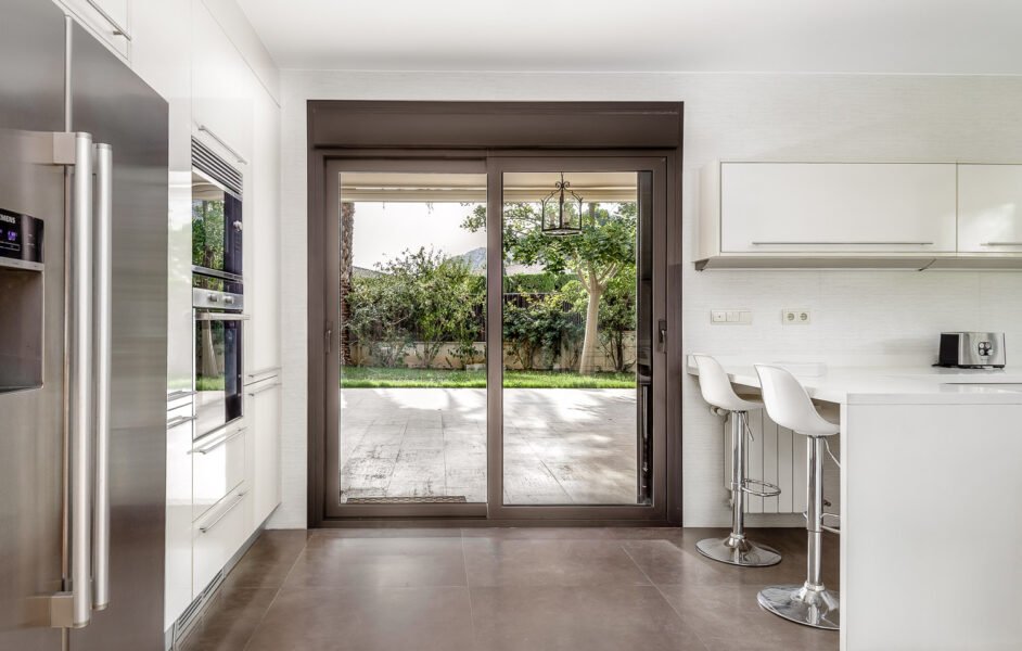 Large fully equipped kitchen and breakfast bar shows views to a beautiful lush green garden with trees for residential