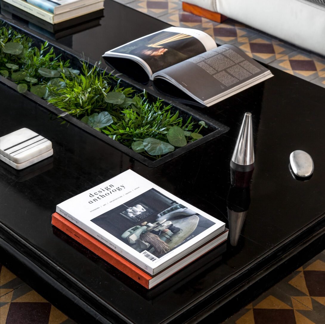 Large black onyx table with plant tray styled with design anthology magazines for interior design look in barcelona