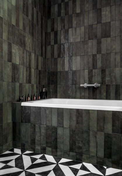 editorial interior styled bathroom features dark green wall tiles with black and white check floors