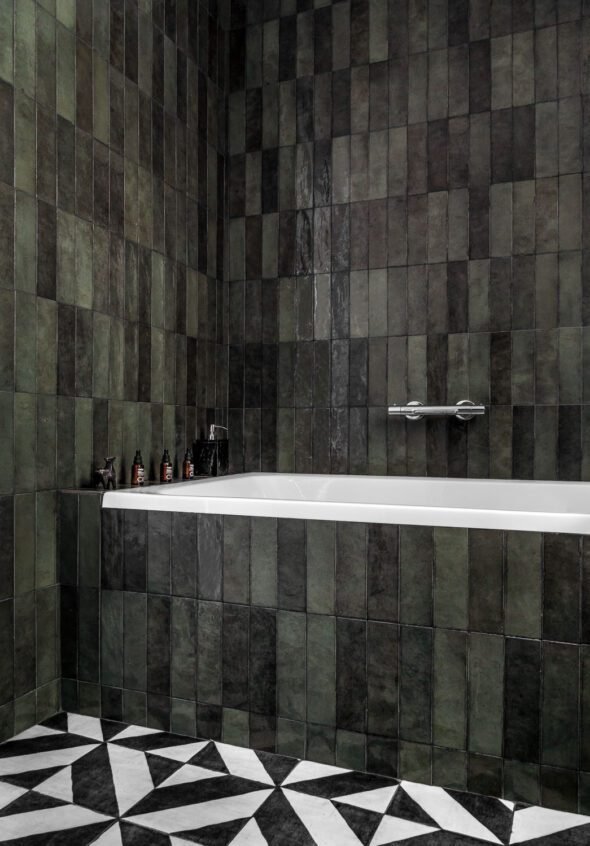 editorial interior styled bathroom features dark green wall tiles with black and white check floors