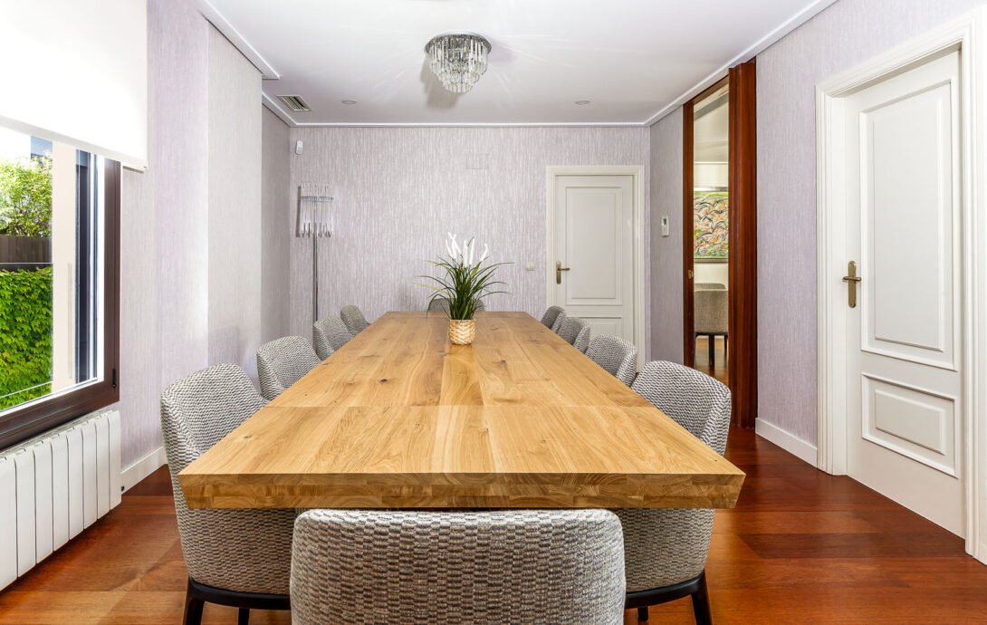 Interior of residential properties dining hall features ten person wooden dining table and chandeliers
