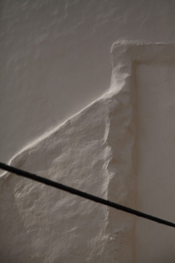 A cream embossed wall with a black cord across it