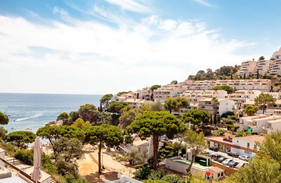 view from terace of Tossa del mar beach with lots of pine trees and residential properties