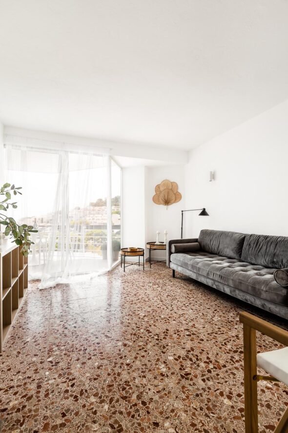 A bright and breezy Residential interior living room with terrazo floor and view to the mountains and sea in Barcelona