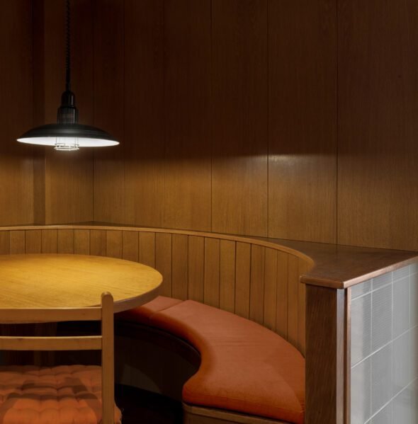 Built in half moon dining nook clad in wood with 1970 black low ceiling light over the table a vintage collectible