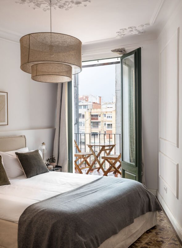 A bedroom dressing in dark green and white with balcony doors open and wooden table and chairs for dining for hospitality,