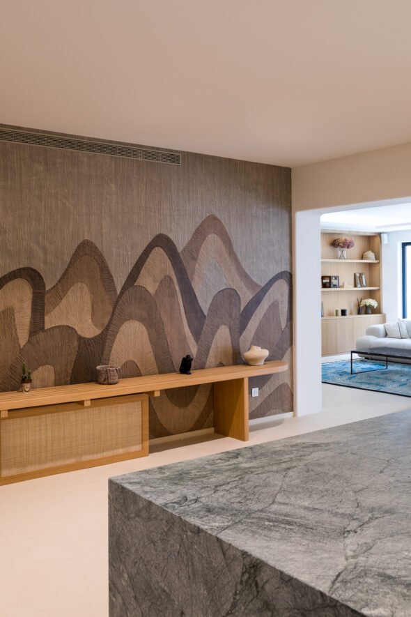 kitchen living room space showcases the textured wall paper design with large dark brown and beige waves and a wooden bench with objects.