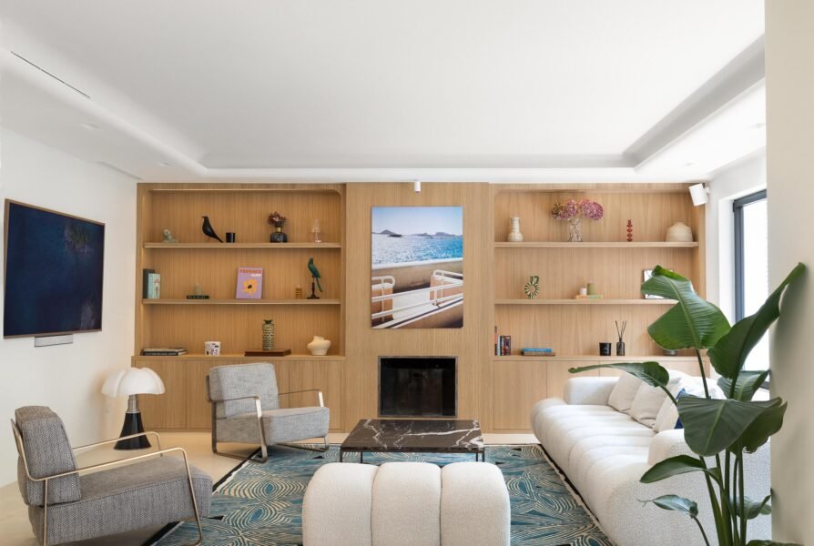 Beautifully styled mid century modern home features a pipistrello lamp, large wooden wall book shelf unit, marble table and boucle modula sofa for interior design magazine.