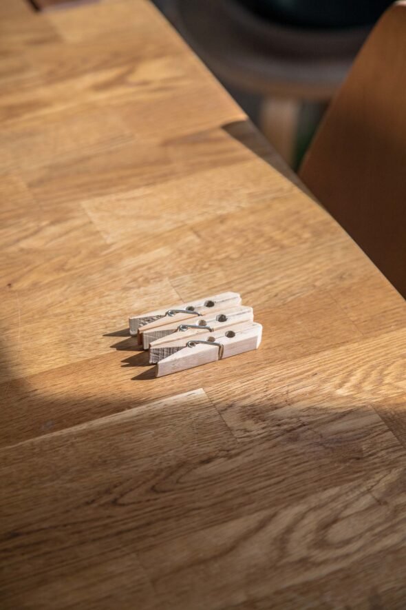Golden hour light on top of a wooden table with three clothes pegs for still life photography