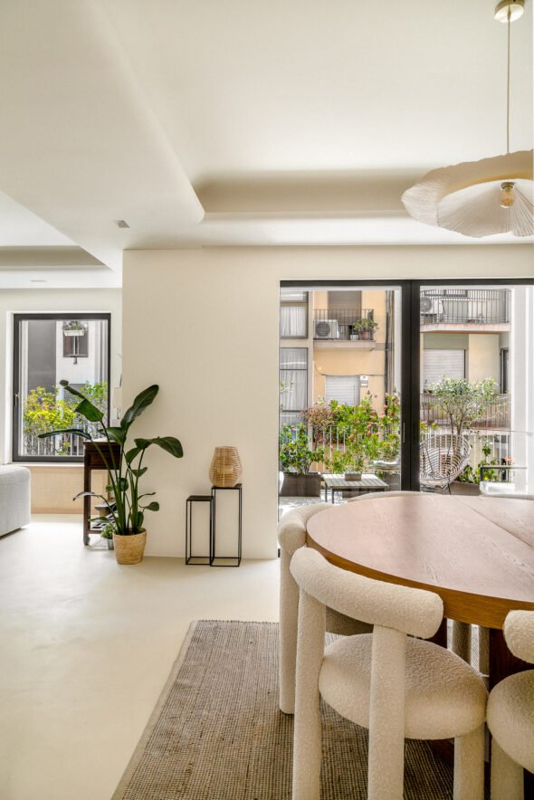 View from a living room at an apartment in Sant Gervasi Barcelona features a wooden table boucle dining charis and view of the outside space decorated with lots of a plants and flowers