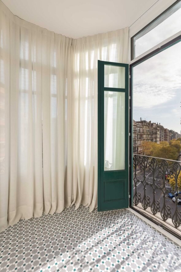 late afternoon diffused golden light beautifully lighting covered gallery with door open looking out onto barcelona tree lined urban street
