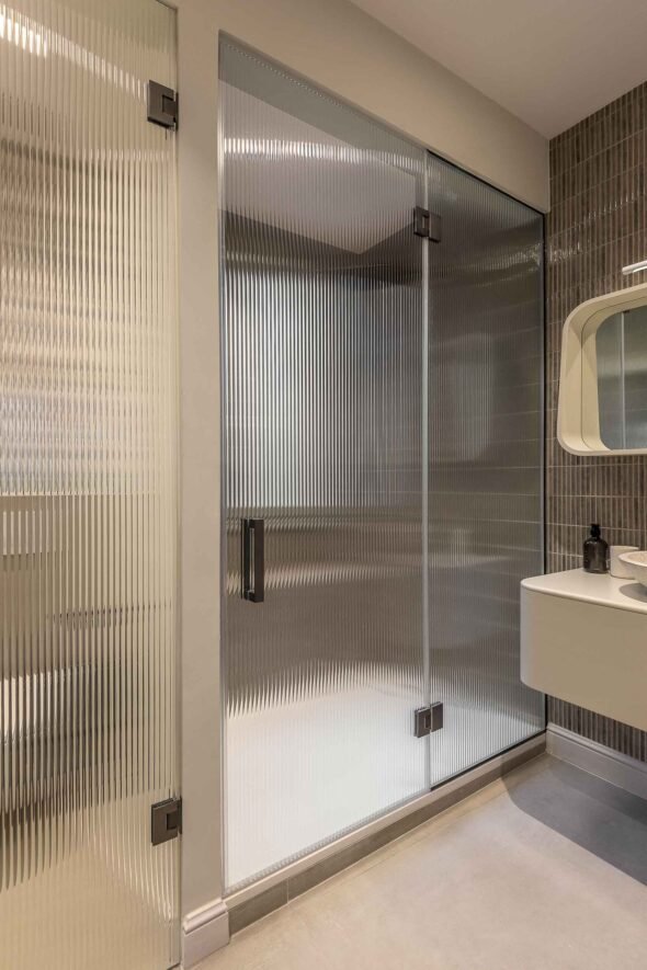 large shower room-natural tones, glass door,sixties mirror, cream floating sink unit and basin